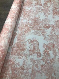 an old wallpaper with pink and white designs on the fabric is laying on top of a wooden table