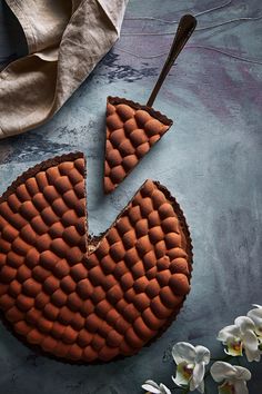 a piece of chocolate cake sitting on top of a table next to flowers and a spoon