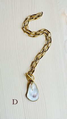 A truly One-of-a-Kind statement piece. Hand painted gold leaf natural oyster shell pendants with gorgeous freshwater pearls, on high quality 12K Gold over brass chain with toggle front closures. Each shell has been harvested in our Charleston, SC rivers and are carefully hand finished to create its one-of-a-kind appearance. No two shells are alike. Each oyster shell has its own story behind its journey to the shore. The size, shape and colors in each one will vary and that is what makes each she Artisan Gold Jewelry With Pearl Charm, Gold Shell Necklace Made Of Mother Of Pearl, Artisan Gold Necklace With Pearl Pendant, Gold Necklace With Pearl Charm, Unique Gold Necklace With Pearl Charm, Gold Shell Necklace With Baroque Pearl Pendant, Gold Shell Jewelry With Adjustable Chain, Gold Shell Jewelry With Pearl Pendant, Gold Pendant Shell Necklace With Adjustable Chain