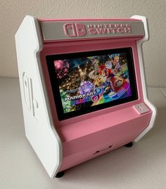 an old fashioned pink and white video game on a table with the screen turned off