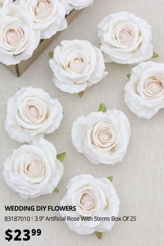 white roses are arranged on a table next to a box