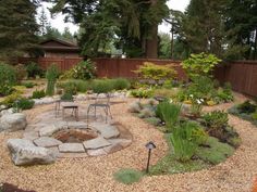 an outdoor fire pit surrounded by rocks and plants