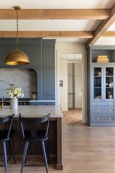 a kitchen with blue cabinets and two black chairs in front of an island counter top