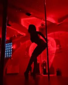 a woman standing in the middle of a room with red light on her face and legs