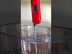 a red electric toothbrush sitting in a glass filled with water on top of a table