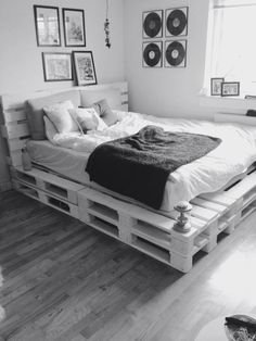 a bed made out of wooden pallets in a room with pictures on the wall