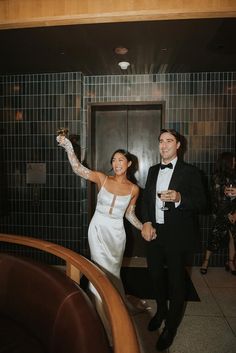 a bride and groom holding champagne flutes in their hands while walking down the aisle at a wedding