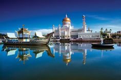 a large white building sitting on top of a lake next to a tall yellow dome