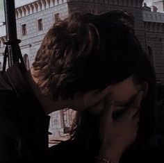 a man and woman kissing in front of a window with an old castle in the background