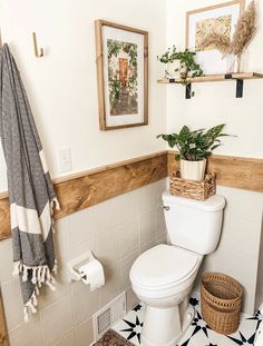 a white toilet sitting in a bathroom next to a towel rack and potted plant