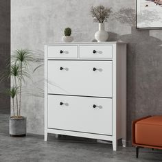 a white chest of drawers sitting next to a potted plant