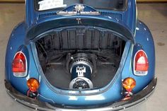 the back end of a blue car with its hood up