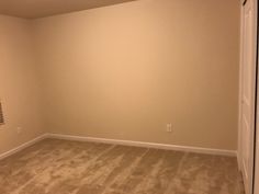 an empty room with carpeting and a radiator on the far wall in front of it