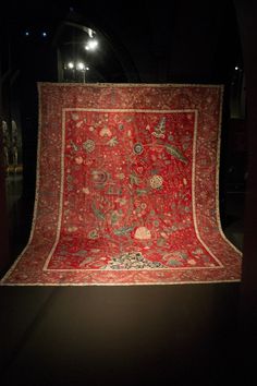 an old red rug is on display in a dark room with other items around it