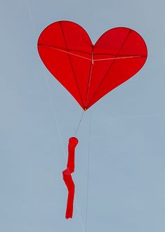 a red heart shaped kite flying in the sky