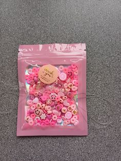 a pink bag filled with lots of buttons on top of a gray carpeted floor