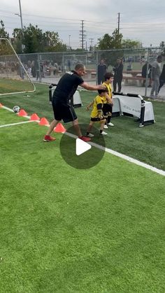 two young boys are playing soccer on the field with an adult watching them from behind