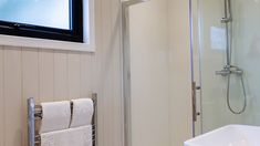 a bathroom with a tv mounted on the wall and a towel rack in front of it