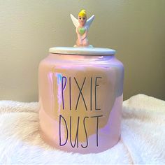 a pink tin can with the words pixie dust written on it and a fairy figurine sitting on top