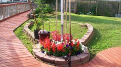 a flag pole in the middle of a flower bed on a deck with flowers around it