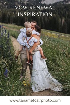 a man and woman holding two children in their arms while walking through tall grass with mountains in the background