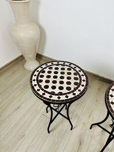 two small tables sitting on top of a hard wood floor next to a white vase