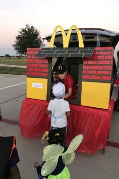 two children are standing in front of a mcdonald's car with a man on top