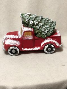 a red truck with a christmas tree on the back is sitting on a white surface