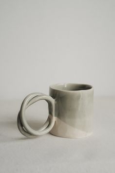 a white coffee cup sitting on top of a table next to a black and white mug