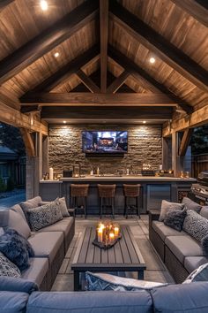 an outdoor living area with couches, tables and a television on the wall above it