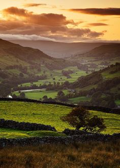 the sun is setting over a green valley