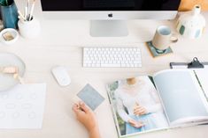 a person's hand is holding a card next to an open book on a desk