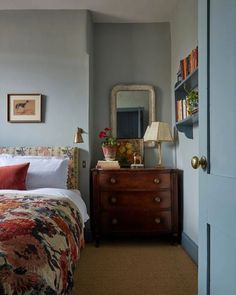 a bedroom with a bed, dresser and mirror on the wall in front of it