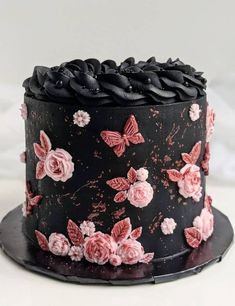 a black cake with pink flowers and butterflies on it