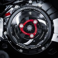 the front wheel of a motorcycle with red and black spokes on it's rim