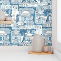 a blue and white wallpaper with buildings in the background on a shelf next to a window