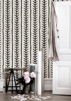 a white and black striped wallpaper next to a vase with flowers on the floor