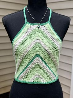 a green and white crocheted top on a mannequin