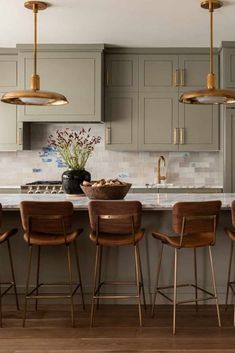 a kitchen with grey cabinets and wooden stools in front of an island countertop