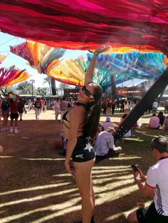 a woman in a bathing suit standing under an umbrella at a festival with other people