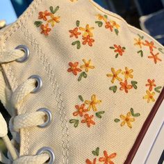 a pair of white shoes with flowers on them are sitting on top of an open book