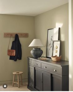 a room with a dresser, lamp and pictures on the wall in front of it