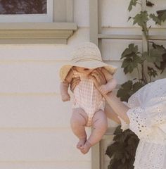 a woman holding a baby up to her face while standing next to a white house