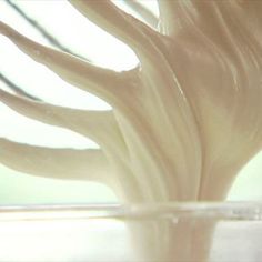 a glass vase filled with white frosting on top of a table