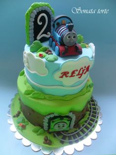 a thomas the train birthday cake with green frosting and fondant decorations on top