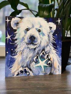 a painting of a polar bear holding a star on a table next to a potted plant