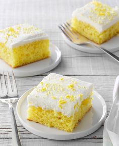 three slices of lemon cake on white plates with forks and napkins next to them