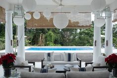 an outdoor living area with couches, tables and lamps hanging from the rafters