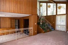 an empty living room with wood paneling and stairs