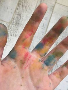 a person's hand covered in multicolored paint